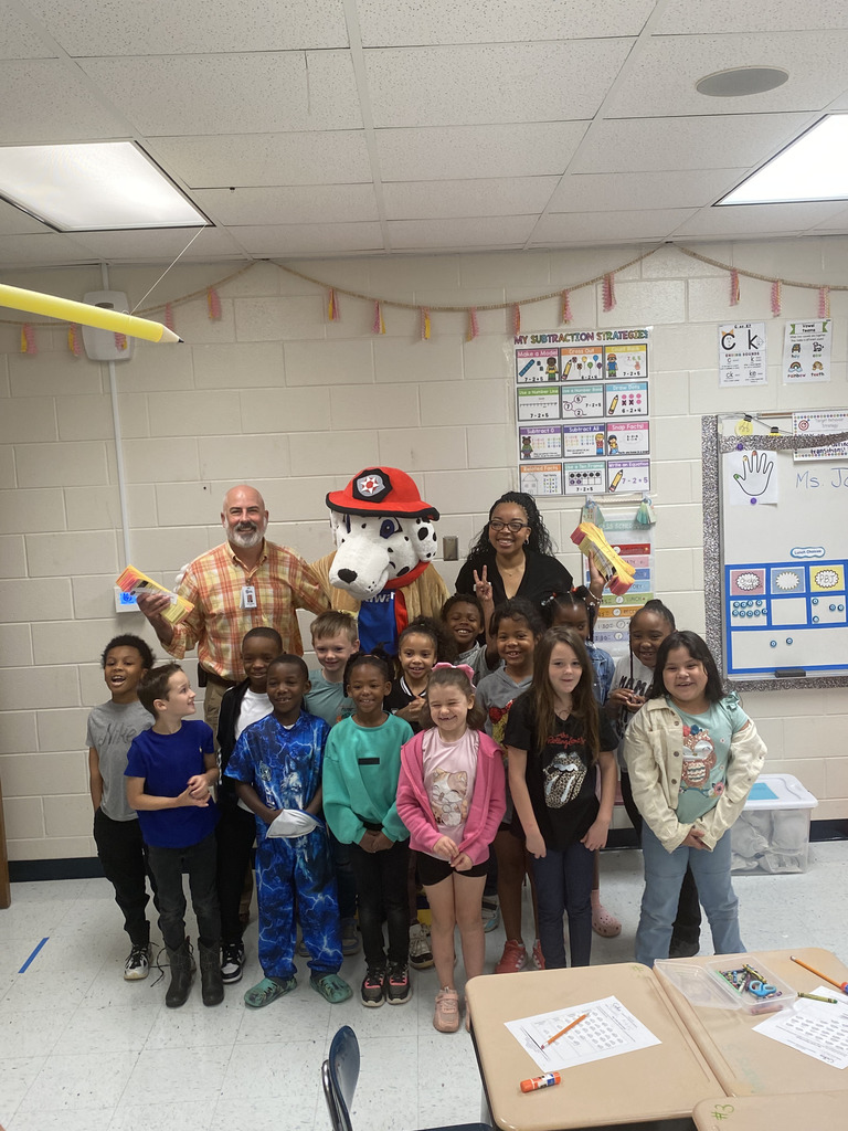 class of students with man, woman, and mascot dog with fireman helmet