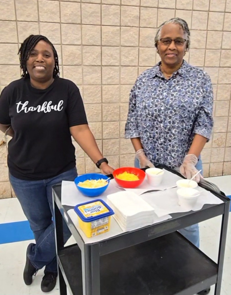 two women at cart with cheese and bowls of grits
