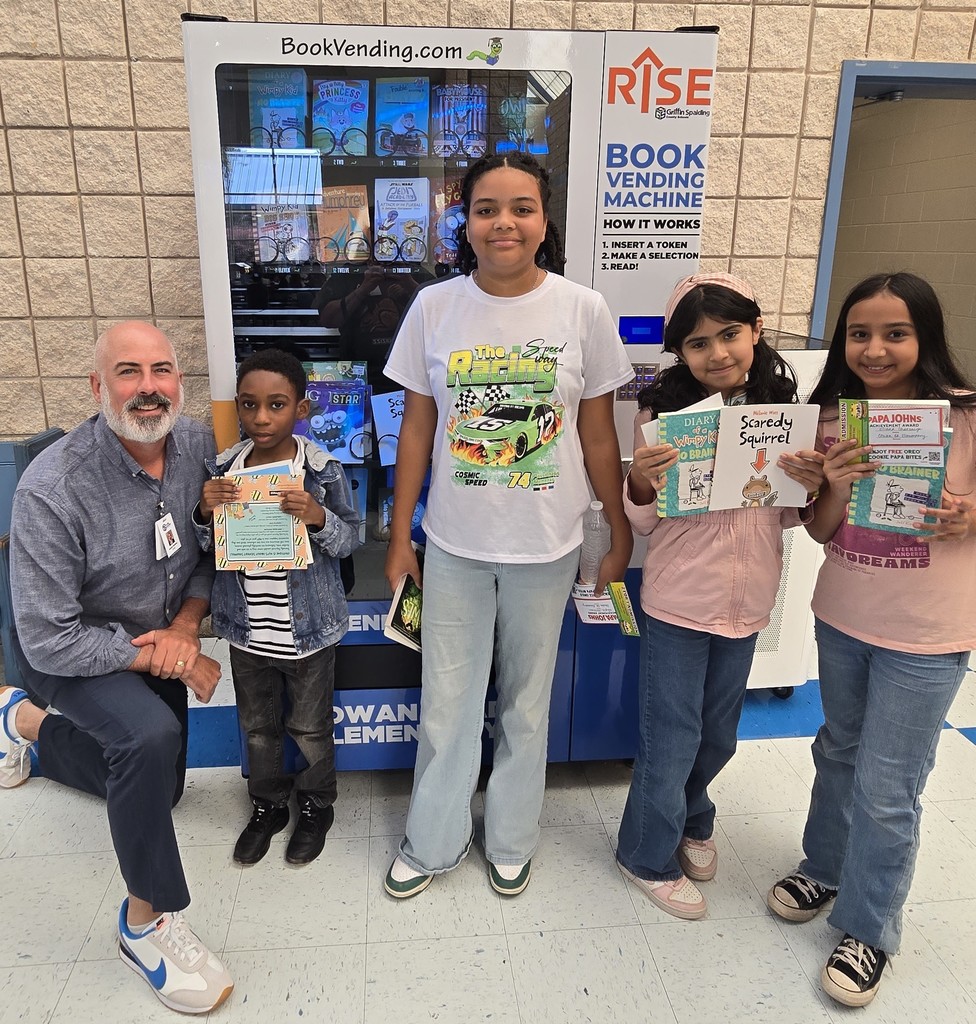 man and 4 students; students are all holding books in front of a book vending machine