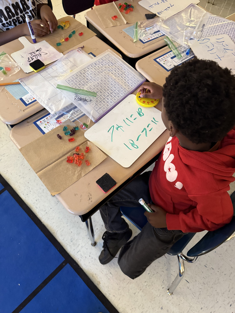 boy at desk with gummy bears, writing math equation