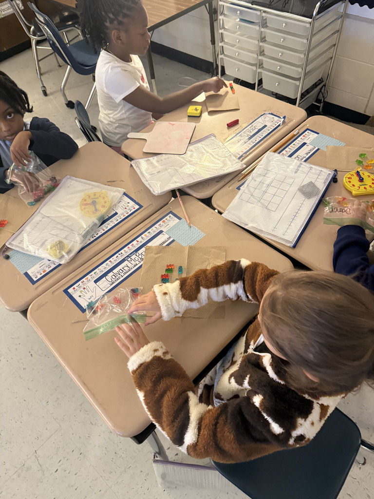 kids at desks with gummy bears, writing math equations