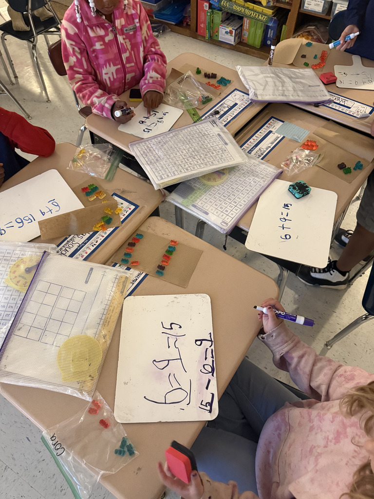 kids at desks with gummy bears, writing math equations