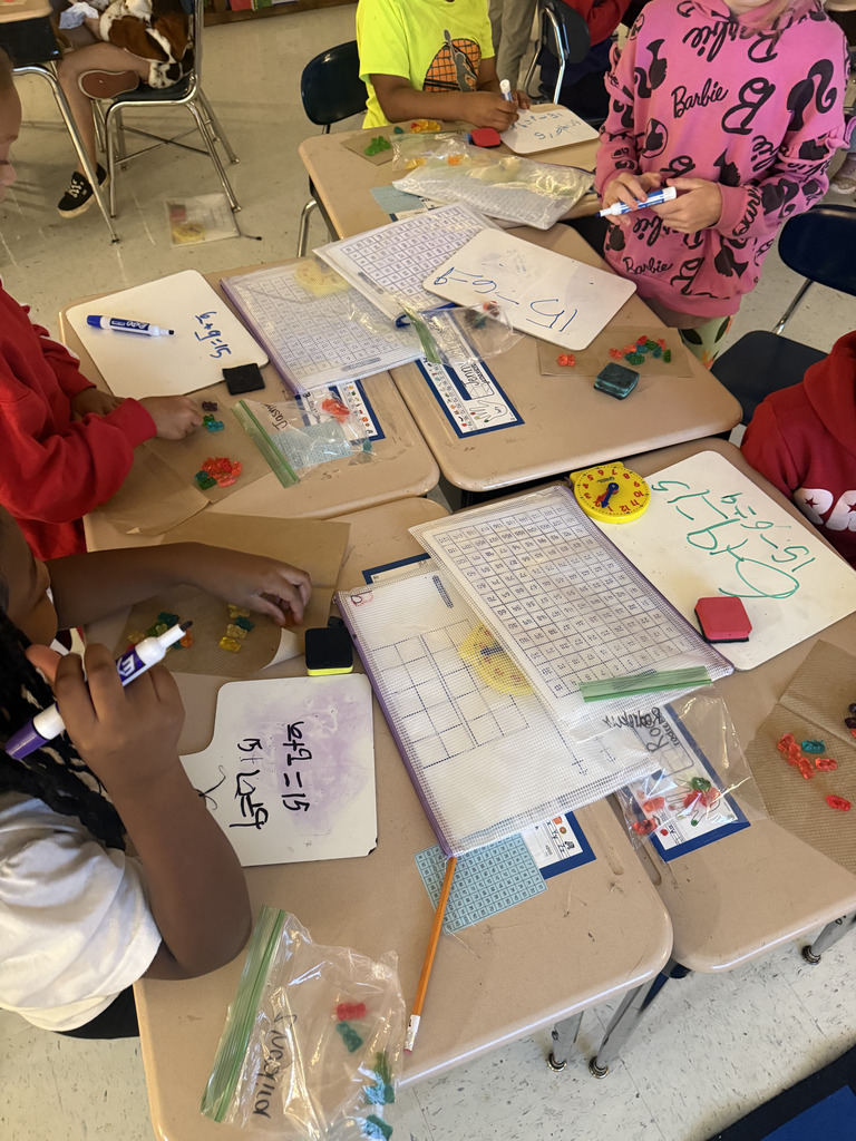 kids at desks with gummy bears, writing math equations