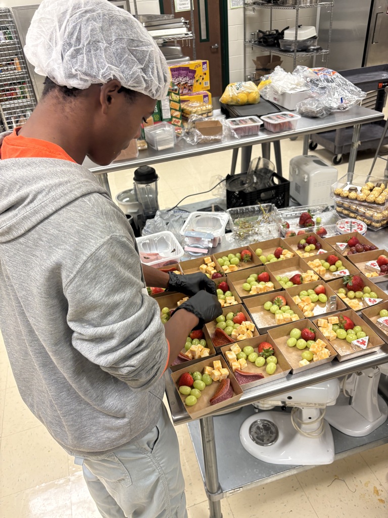 A student placing fruit and cheese into charcuterie boxes