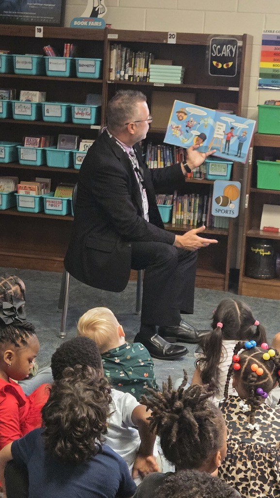man reading in front of small children