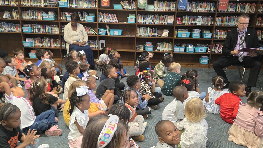 man reading in front of small children