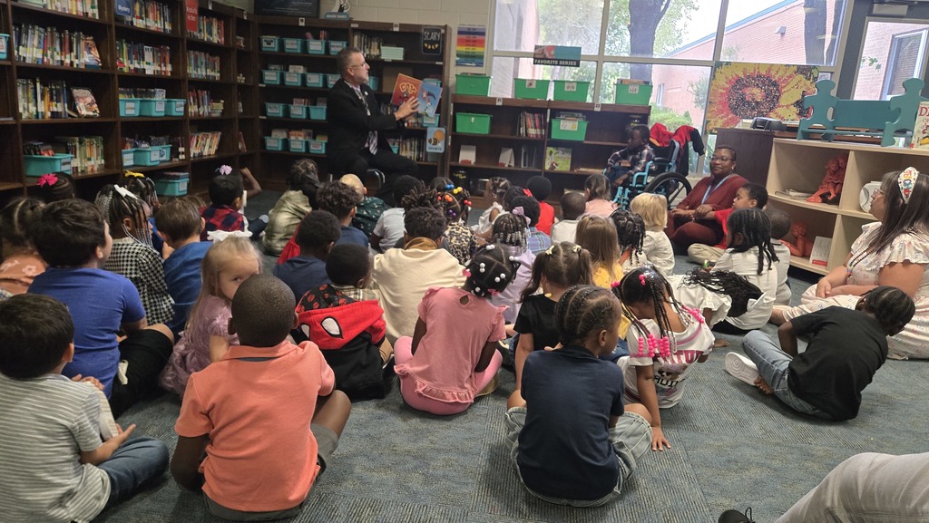 man reading in front of small children