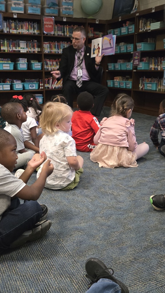 man reading in front of small children