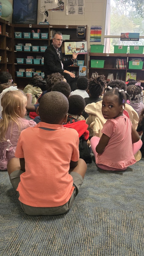 man reading in front of small children