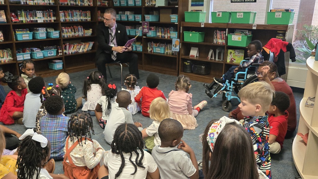man reading in front of small children