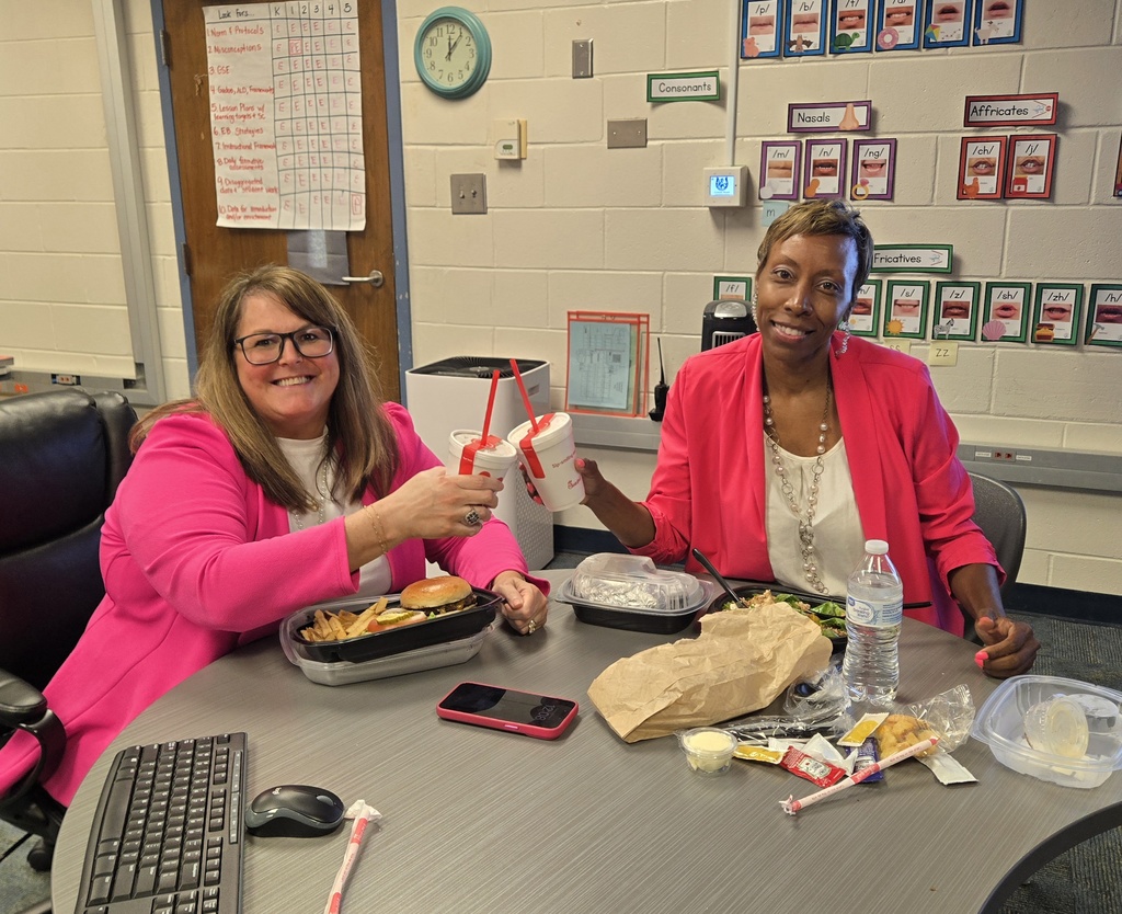 two women, both wearing pink, at a table with food