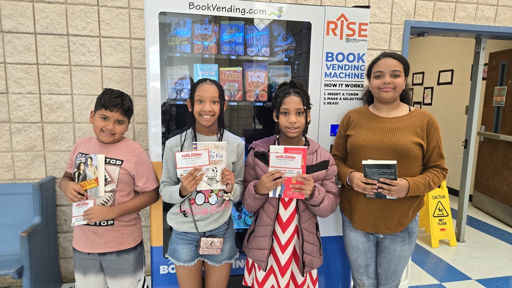 pic of 4 students holding book and certificate to Papa John's in front of school book vending machine