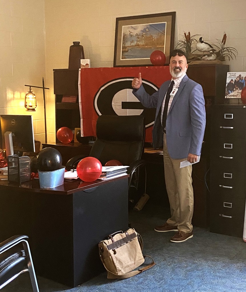 man standing in office in front of UGA "flag" with balloons