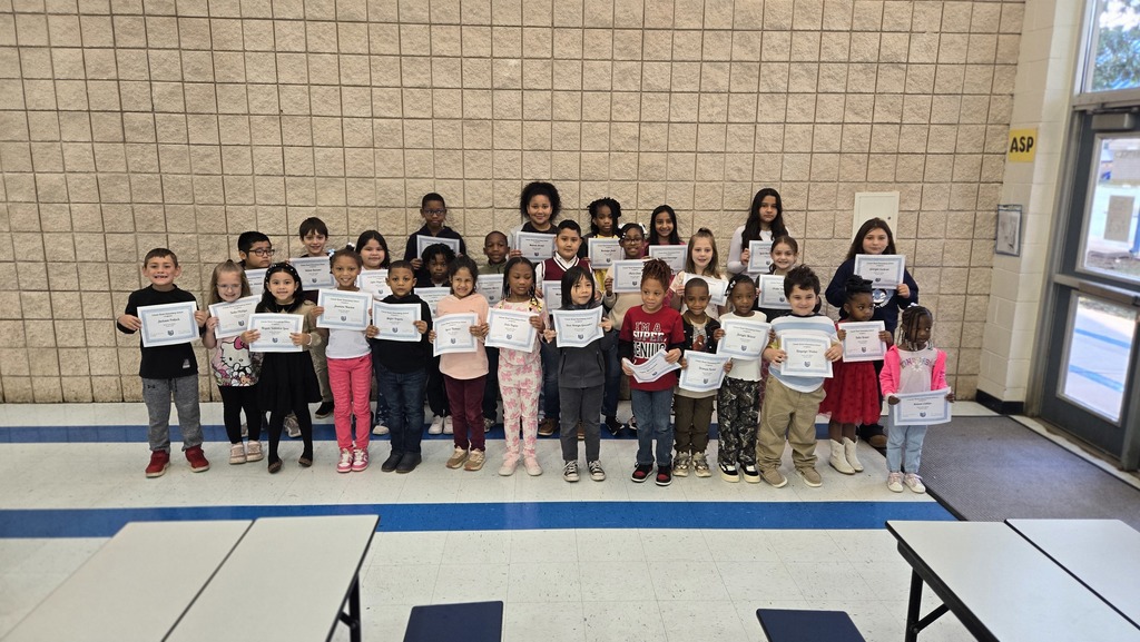 group of students in front of wall with certificates