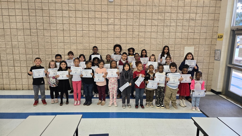 group of students in front of wall with certificates
