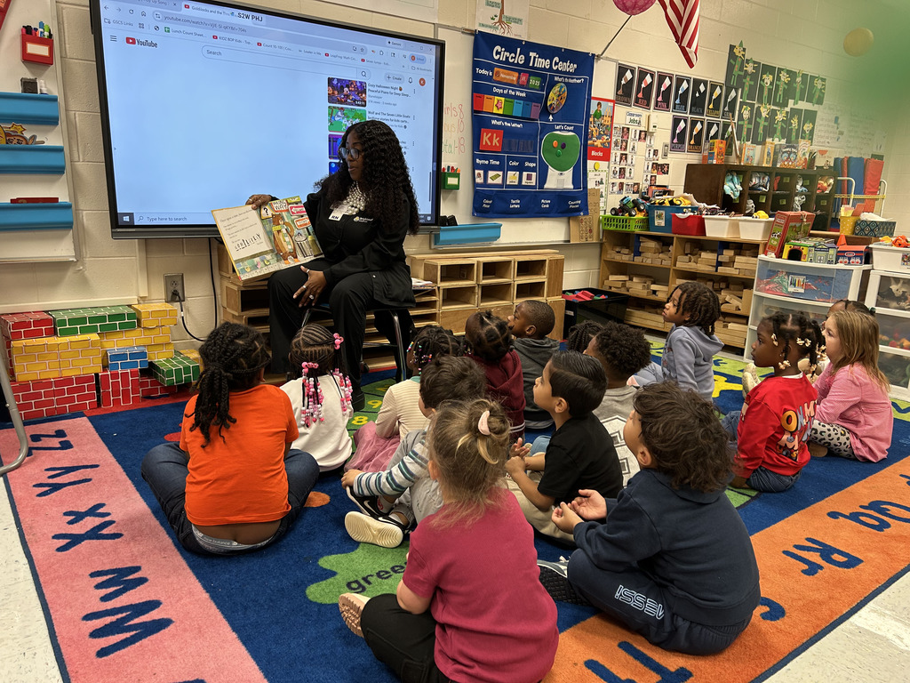 adult reading in front of class of young children