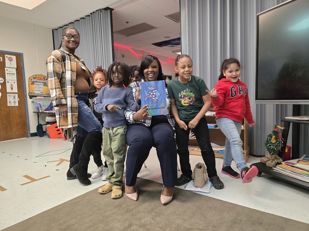 adult holding books in a group of young children