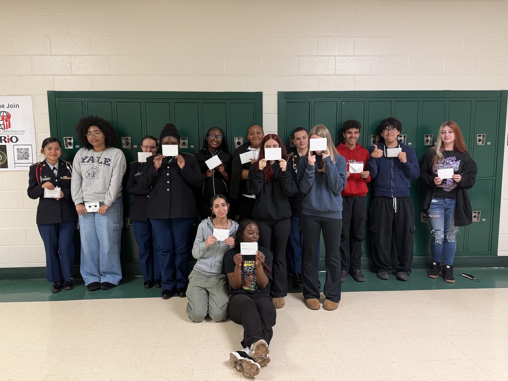 Students hold up their thank you letters to veterans