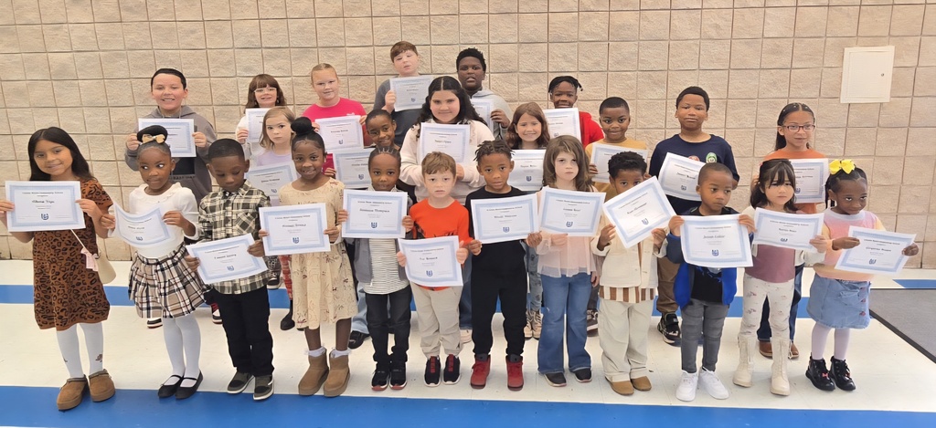 group of students holding certificates in front of wall