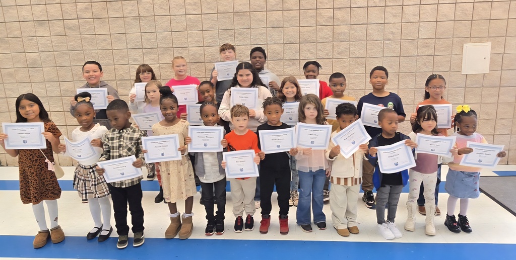 group of students holding certificates in front of wall