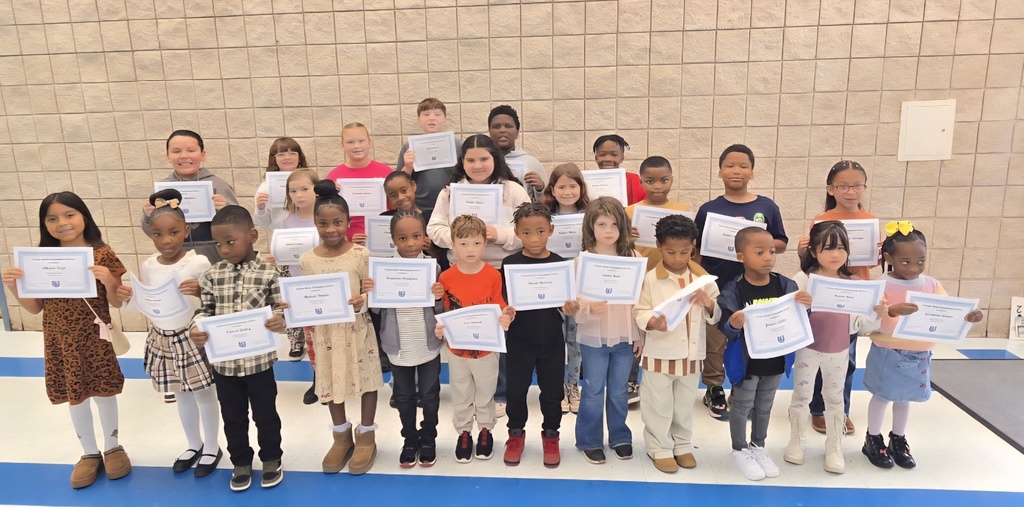 group of students holding certificates in front of wall