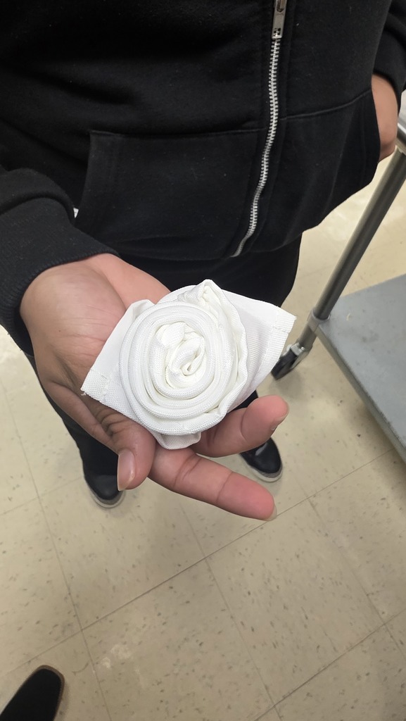 A student shows a cloth napkin folded as a rose