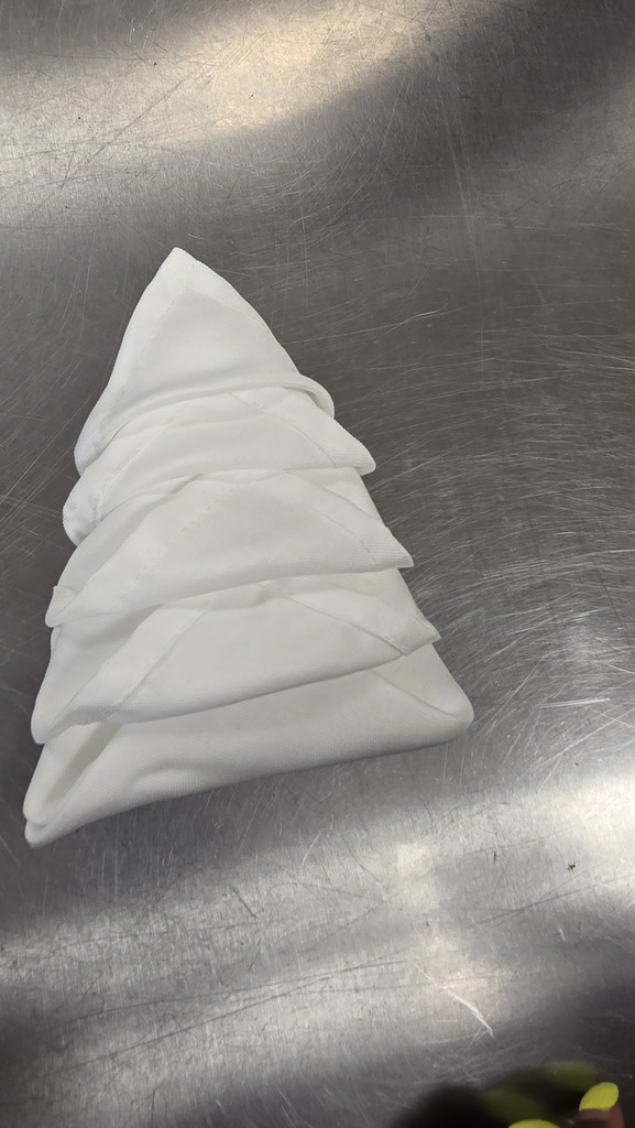 Students practice folding cloth napkins in a nested shape