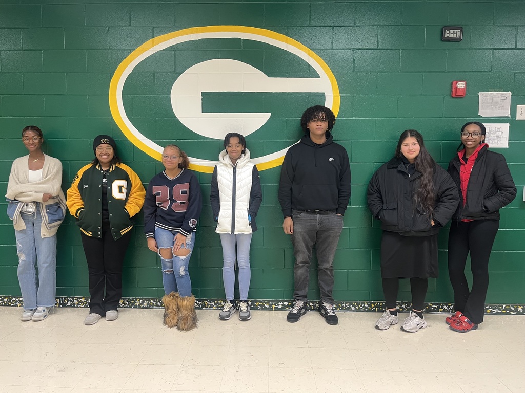 Scholars in front of school logo