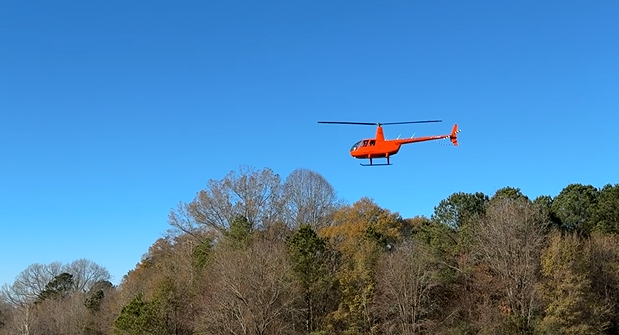 helicopter in sky above tree line