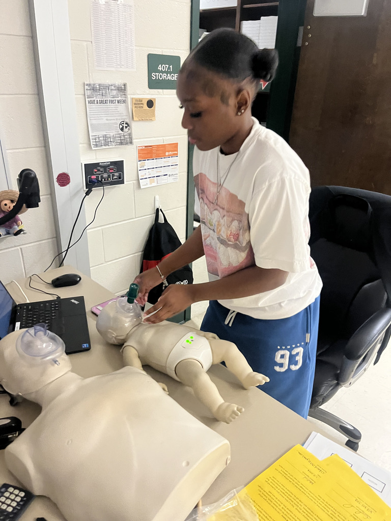 A student practices CPR on an infant dummy
