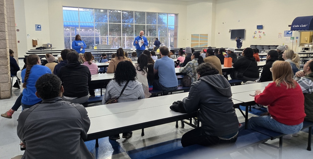families at tables, man in front speaking