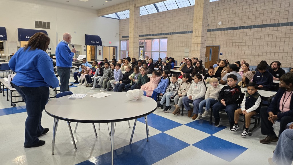 families at tables, man in front speaking