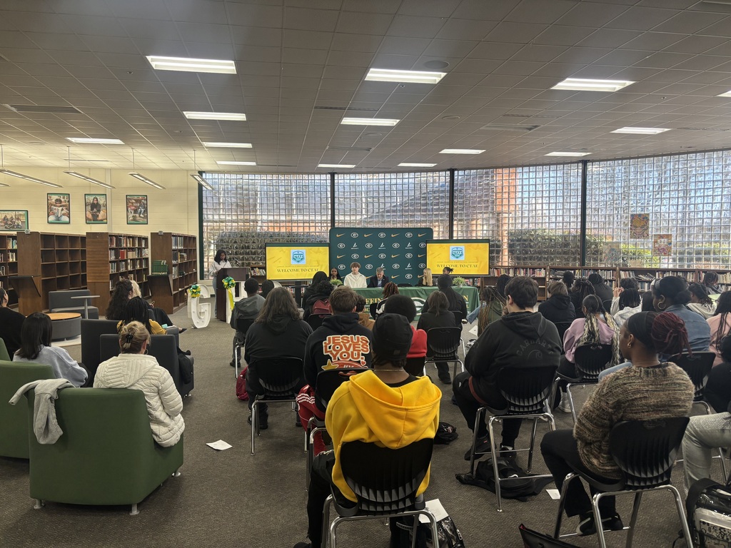Students seated with the mayor in front of an audience of students and community members