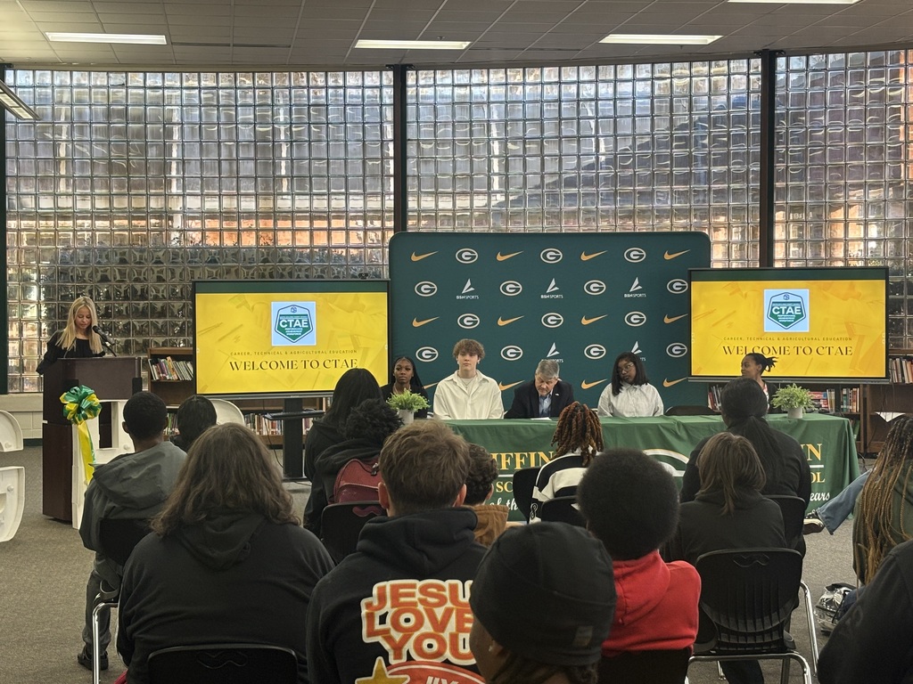Students seated with the mayor in front of an audience of students and community members