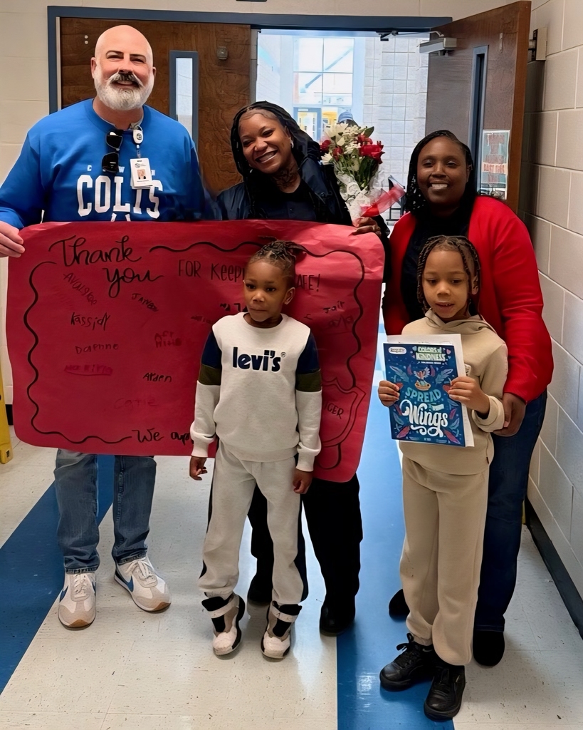 Pic of security officer with banner, two administrators, and two children
