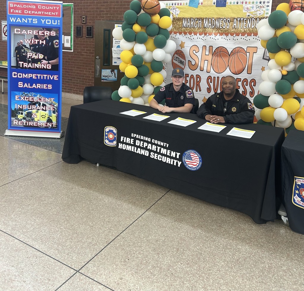 Firefighters sit at a table in the school commons to recruit students