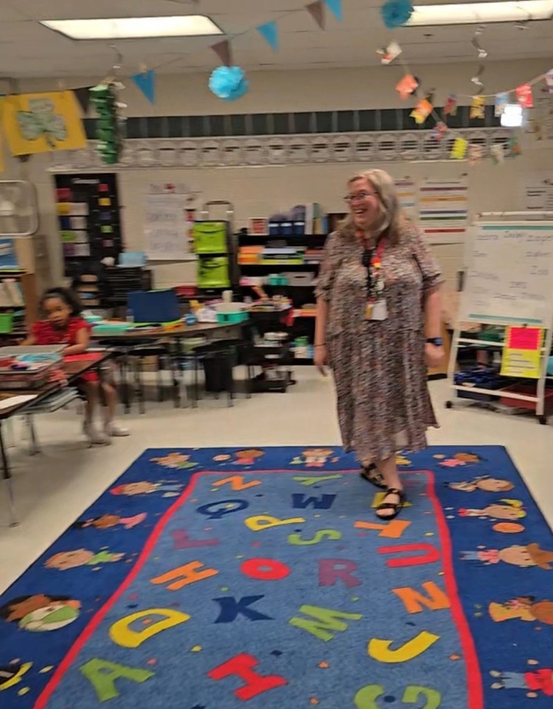 woman smiling at students as she walks across classroom