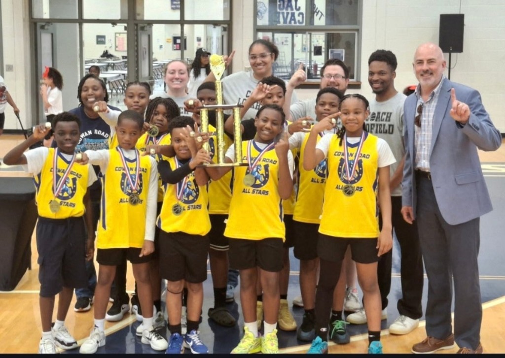 basketball team with coaches and admin, holding up #1 and trophy