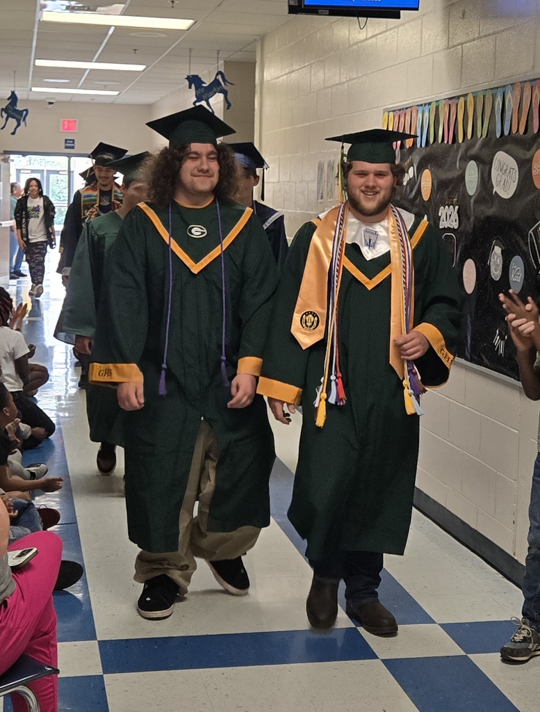 Seniors (in cap and gown) walking in elementary hall