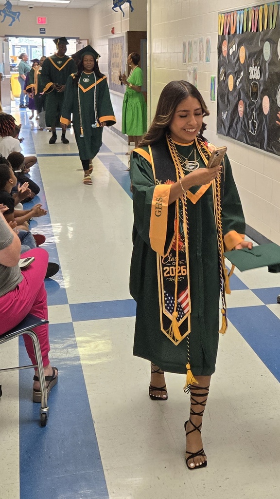 Seniors (in cap and gown) walking in elementary hall