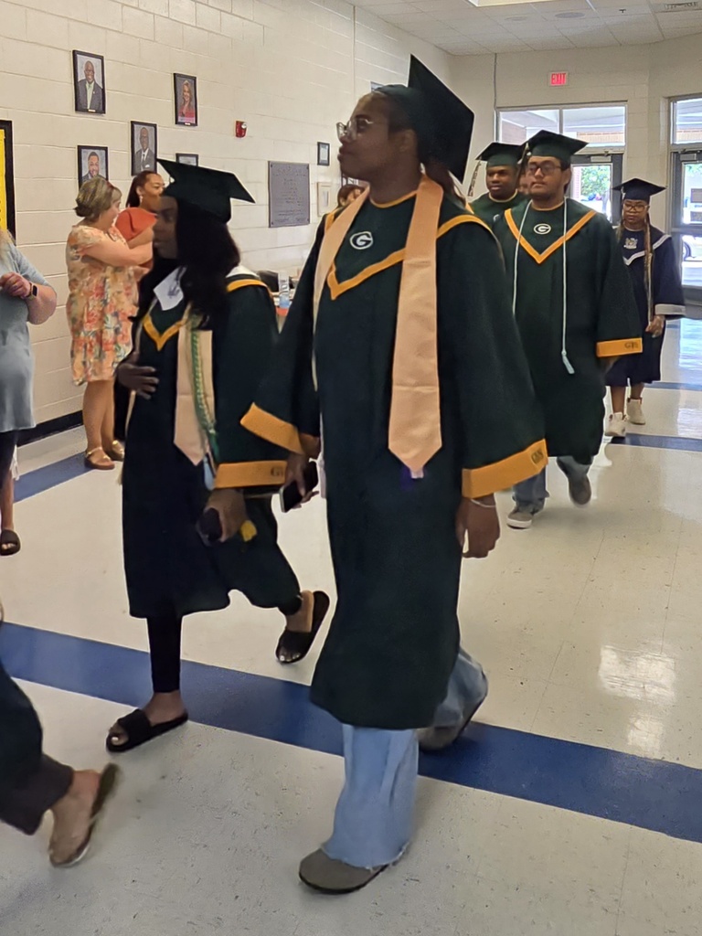 Seniors (in cap and gown) walking in elementary hall