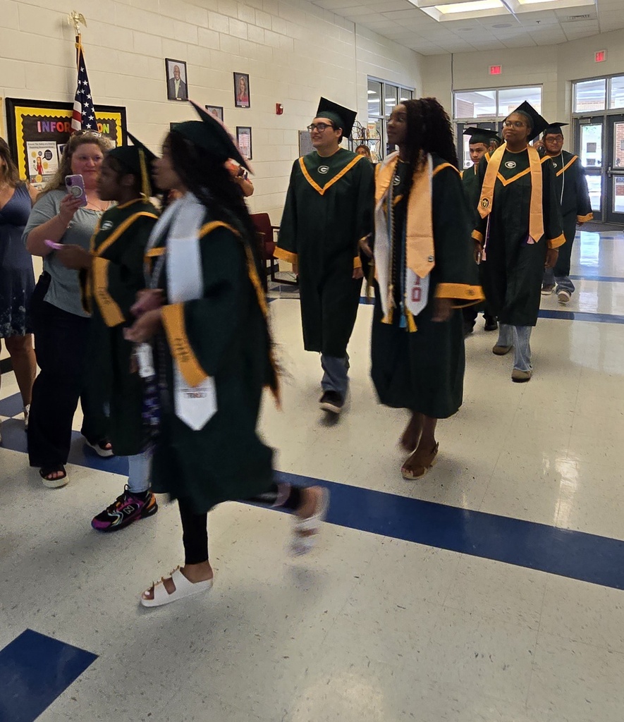 Seniors (in cap and gown) walking in elementary hall