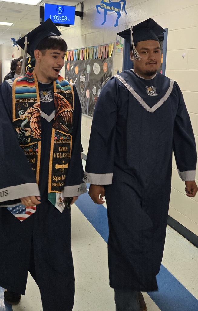 Seniors (in cap and gown) walking in elementary hall