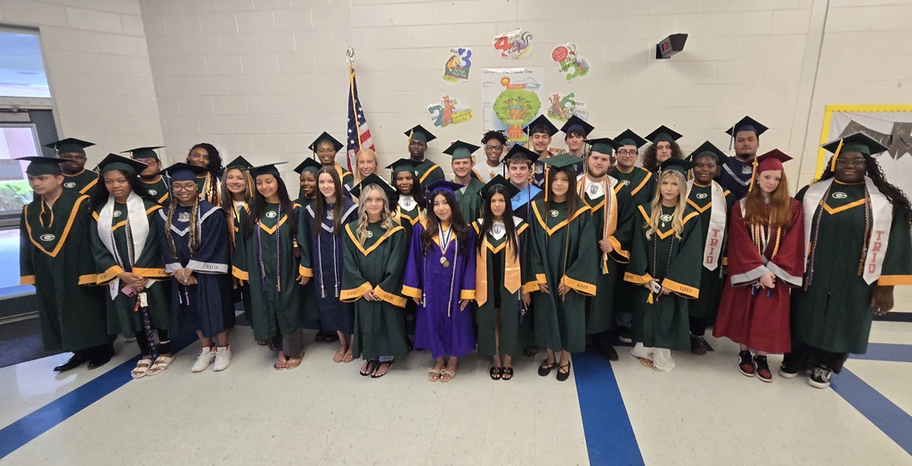 Seniors (in cap and gown) standing in elementary hall