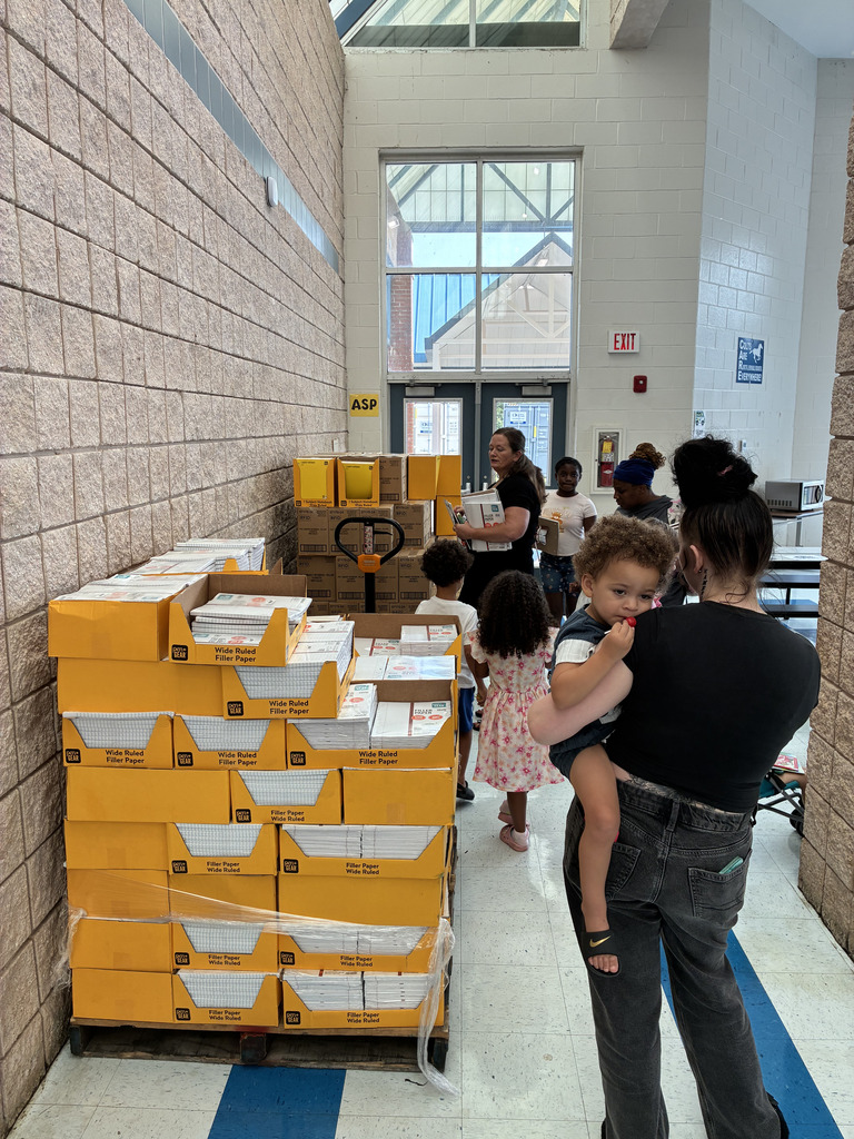 adults and children picking up paper from pallets