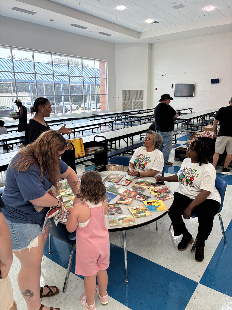 adults and students at book table in cafeteria
