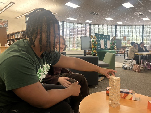 A student places a JENGA tile on top of the tower