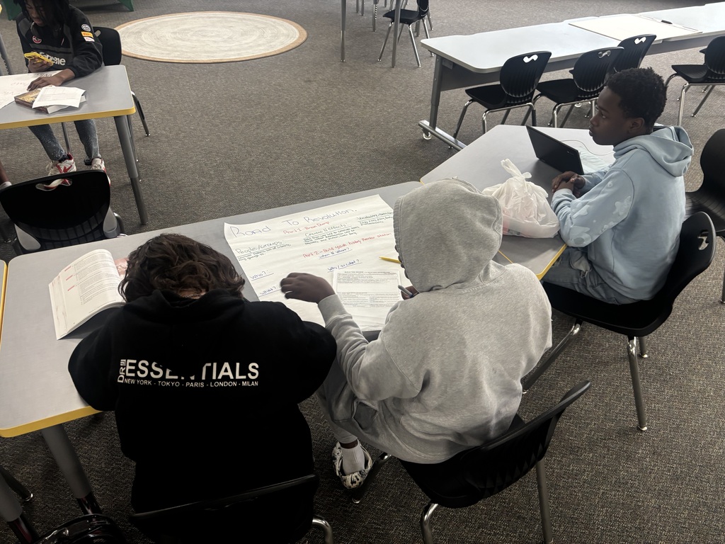 Students reference their textbook to create posters about historical events