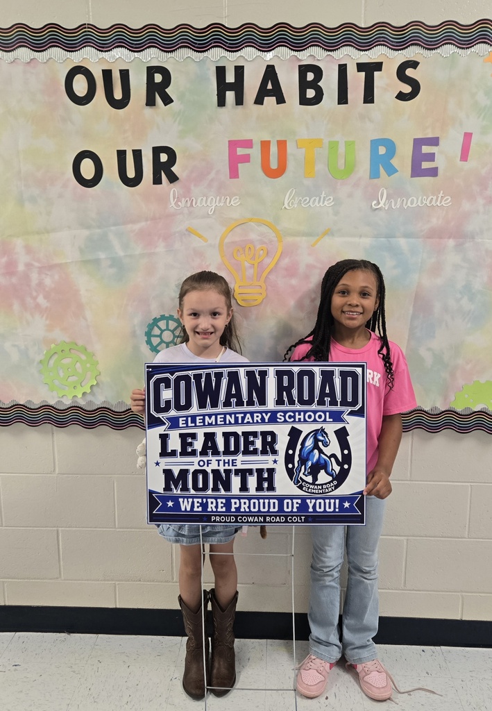 two girls holding a sign reading "Cowan Road Leader of the Month....we're proud of you"