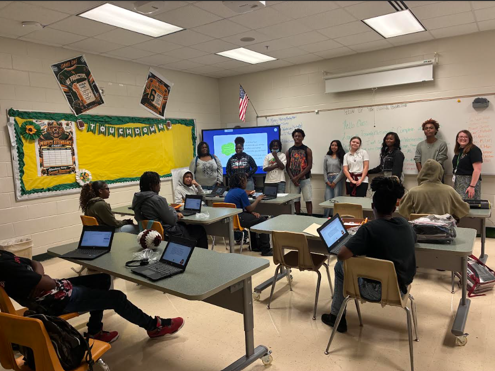 A group of students stands at the front of the classroom singing